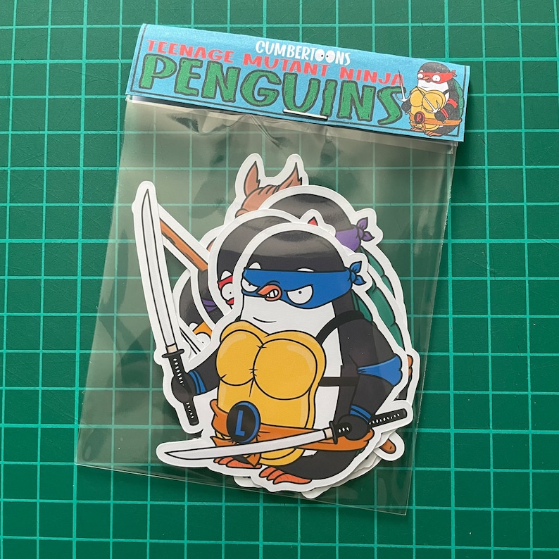 Puede incluir: Un conjunto de cuatro pegatinas de Teenage Mutant Ninja Penguin. Las pegatinas muestran a los ping&uuml;inos vestidos como las Tortugas Ninja, cada uno con sus colores y armas caracter&iacute;sticos. Las pegatinas est&aacute;n empaquetadas en una bolsa de pl&aacute;stico transparente con un encabezado que dice "Cumbertoons Teenage Mutant Ninja Penguins".