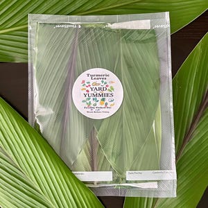 May include: A vacuum-sealed plastic bag containing fresh green turmeric leaves with purple stems. A circular white label features the text Yard Yummies, Turmeric Leaves, Freshly Picked On, and Wash Before Using, surrounded by colorful fruit and vegetable icons.