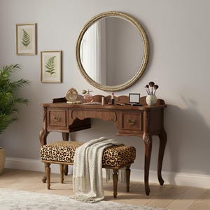 Op de afbeelding: Een vintage kaptafelset met een ronde spiegel, een houten bureau en een bankje met luipaardprint. Het bureau heeft lades en is versierd met make-up items. Twee ingelijste varenprints hangen aan de muur.
