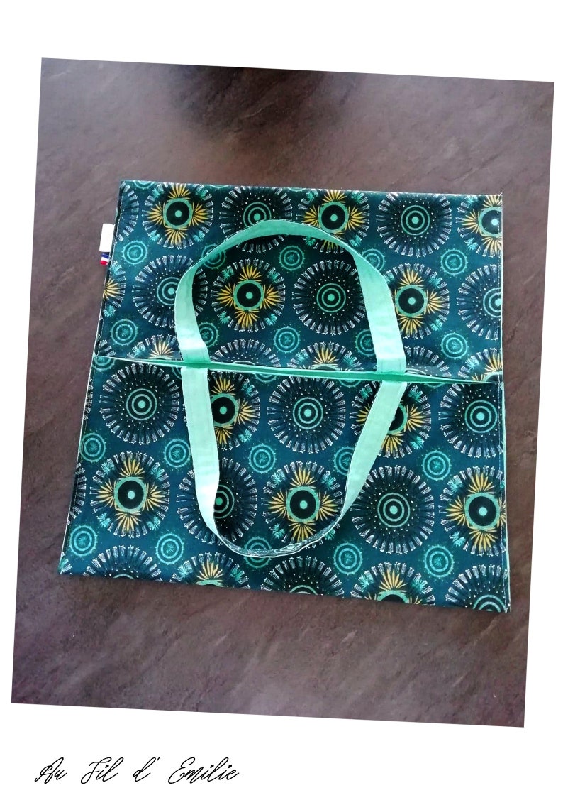 May include: A green tote bag with a geometric pattern of circles and yellow accents. The bag has two light green straps.