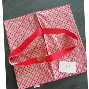 May include: Red and white fabric tote bag with red handles and a small white tag with the text "Au Fil d'Emilie".