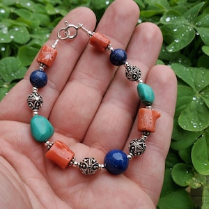May include: A bracelet with turquoise, coral, and lapis lazuli beads, interspersed with silver beads with intricate designs.