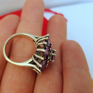 May include: A silver ring with a cluster of purple amethyst stones set in a delicate, intricate design.