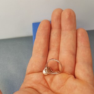 May include: A silver ring with a single white pearl set in a silver setting.