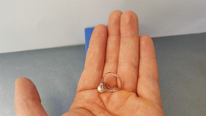 May include: A silver ring with a single white pearl set in a silver setting.