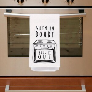 May include: White kitchen towel with black text that reads "When in doubt, pull it out."  The text is accompanied by a black and white illustration of a stove.