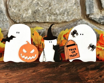 Può includere: Decorazioni a tema Halloween con figure di fantasmi bianchi con accenti di pipistrelli, streghe e ragni. Sono inclusi anche una zucca arancione e un gatto nero. Un fantasma tiene in mano una borsa con la scritta "Trick or Treat".