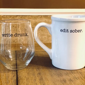 Puede incluir: Una taza de cerámica blanca con el texto "edit sober." junto a un vaso transparente con el texto "write drunk."