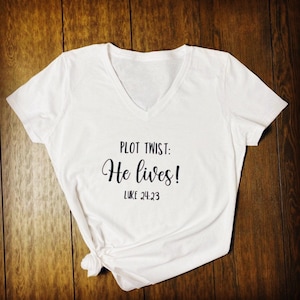May include: White v-neck t-shirt with black text that reads "PLOT TWIST: He lives! LUKE 24:23".