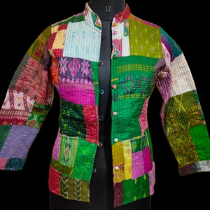 Puede incluir: Una chaqueta de patchwork con una variedad de colores y patrones, incluyendo verde, rosa, morado y blanco. La chaqueta tiene un cuello mandar&iacute;n y un cierre de bot&oacute;n.