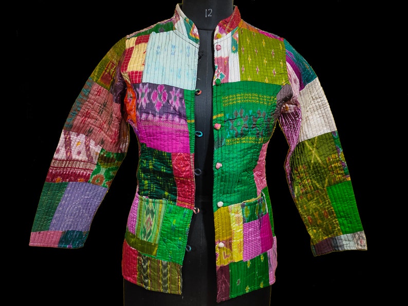 Puede incluir: Una chaqueta de patchwork con una variedad de colores y patrones, incluyendo verde, rosa, morado y blanco. La chaqueta tiene un cuello mandar&iacute;n y un cierre de bot&oacute;n.