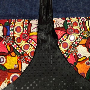 May include: A denim jacket with colorful embroidered patches and mirror embellishments. The patches feature floral and geometric designs in shades of red, orange, yellow, green, blue, and white.