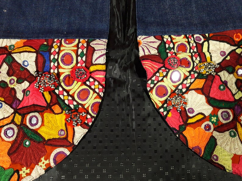 May include: A denim jacket with colorful embroidered patches and mirror embellishments. The patches feature floral and geometric designs in shades of red, orange, yellow, green, blue, and white.