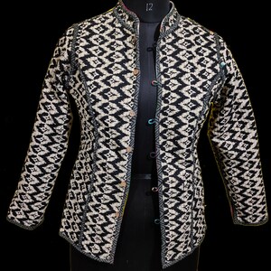 Puede incluir: Una chaqueta con estampado en blanco y negro con cuello mandar&iacute;n y cierre de botones. La chaqueta tiene un dise&ntilde;o acolchado y una silueta ajustada.