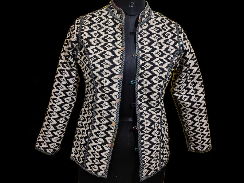 Puede incluir: Una chaqueta con estampado en blanco y negro con cuello mandar&iacute;n y cierre de botones. La chaqueta tiene un dise&ntilde;o acolchado y una silueta ajustada.