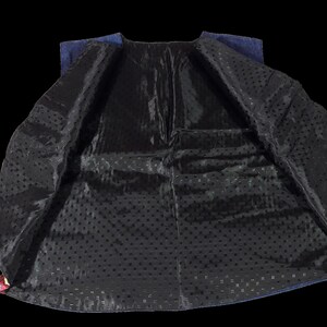 May include: A blue denim vest with a black lining featuring a small polka dot pattern. The vest is unbuttoned and turned inside out, showing the lining.