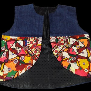 May include: A denim vest with colorful embroidered patches and mirror accents. The vest has a black lining with a dotted pattern.