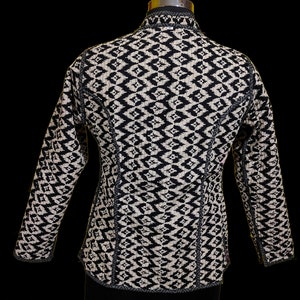 Puede incluir: Chaqueta con estampado en blanco y negro, cuello alto y mangas largas.