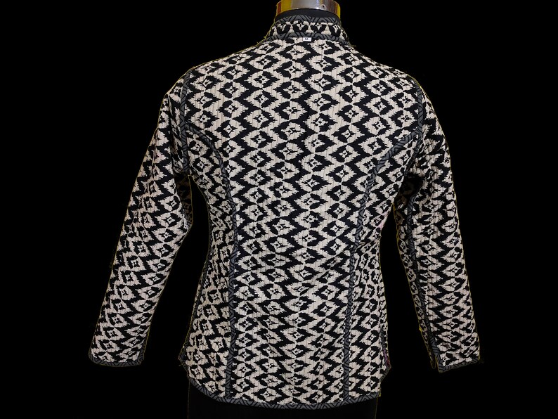 Puede incluir: Chaqueta con estampado en blanco y negro, cuello alto y mangas largas.