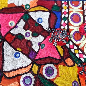 May include: A colorful textile with intricate embroidery and mirror embellishments. The fabric features a variety of geometric and floral patterns in shades of red, pink, green, blue, yellow, and white.