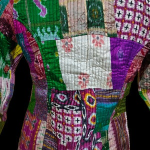 Puede incluir: Una chaqueta de patchwork hecha de diferentes telas en tonos de verde, morado, rosa y blanco. La chaqueta tiene un dise&ntilde;o acolchado y est&aacute; hecha de seda.