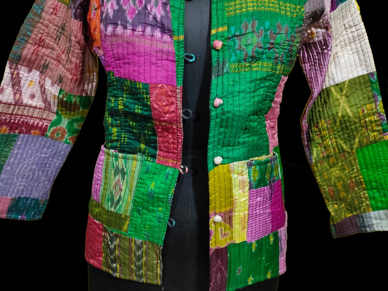 Puede incluir: Una chaqueta acolchada de patchwork con cierre de bot&oacute;n. La chaqueta est&aacute; hecha de varias telas en tonos de verde, morado, rosa y marr&oacute;n. La tela tiene un patr&oacute;n tejido.