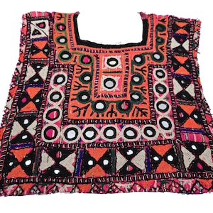 May include: A colorful embroidered fabric panel with a geometric pattern and small round mirrors. The fabric is a mix of pink, orange, black, white, and blue.