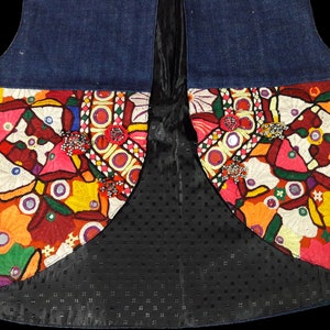 May include: A denim vest with colorful embroidered floral patterns and mirrored accents. The vest has a black lining with a dotted pattern.