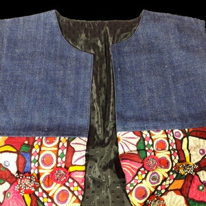May include: A denim vest with colorful embroidery and embellishments. The vest has a black lining and a V-neck.