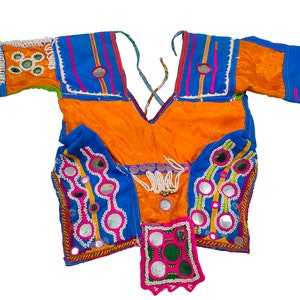 May include: A bright orange and blue top with mirror embellishments and colourful embroidery. The top has a V-neck and short sleeves.