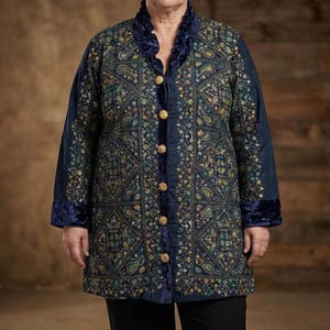 May include: A navy blue, long-sleeved coat with an intricate paisley pattern in shades of green, gold, and blue. The coat features a velvet collar, cuffs, and button detailing. The buttons are gold-colored.