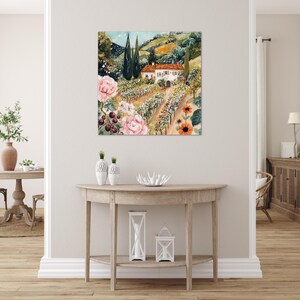 a living room with a large painting of a countryside landscape hanging on the wall above a wooden console table.