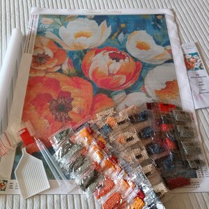 a diamond painting kit with a large floral design, along with various tools and materials for creating a diamond-patterned artwork.