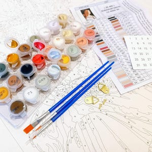 a table topped with lots of paint and brushes