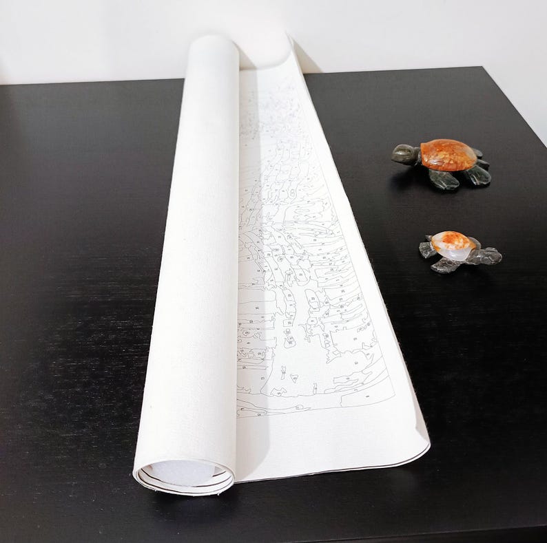 a roll of paper with a drawing of a turtle on it, placed on a black surface next to two small turtle figurines.