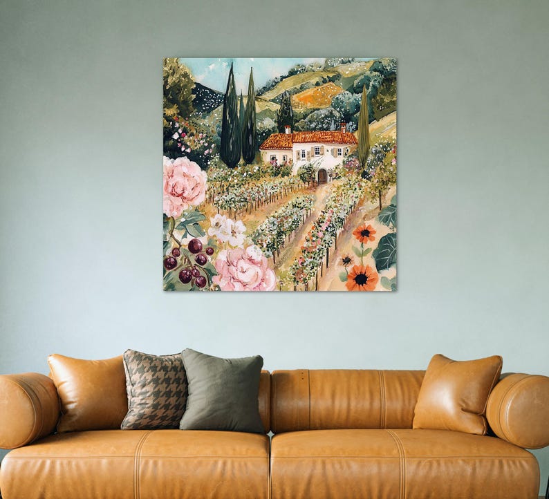 a large painting of a countryside scene with a house, flowers, and trees hanging on a wall above a brown leather couch.