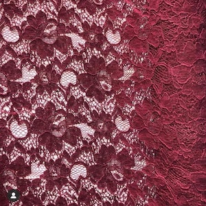 May include: Close-up of a burgundy lace fabric with a delicate floral pattern.