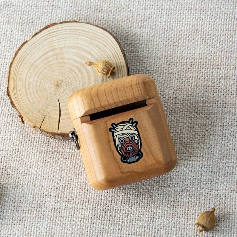 May include: A wooden case with a hinged lid for storing small items. The case has a graphic of a character with a bandage-wrapped head and a red face.