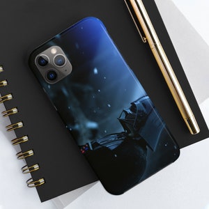 May include: A black phone case with a dark blue background and a white, snowy scene. Darth Vader's helmet is visible in the foreground.