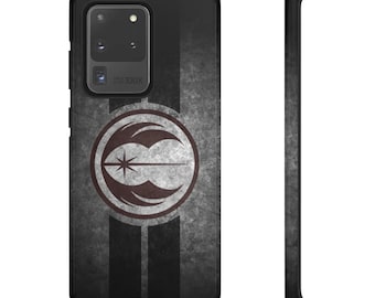 Puede incluir: Una funda de teléfono negra con un fondo gris y negro desgastado. Un símbolo blanco y gris con una estrella en el centro está en la funda. El símbolo está rodeado por un círculo rojo. La funda tiene una carcasa de cámara negra con el texto "100X" impreso en ella.
