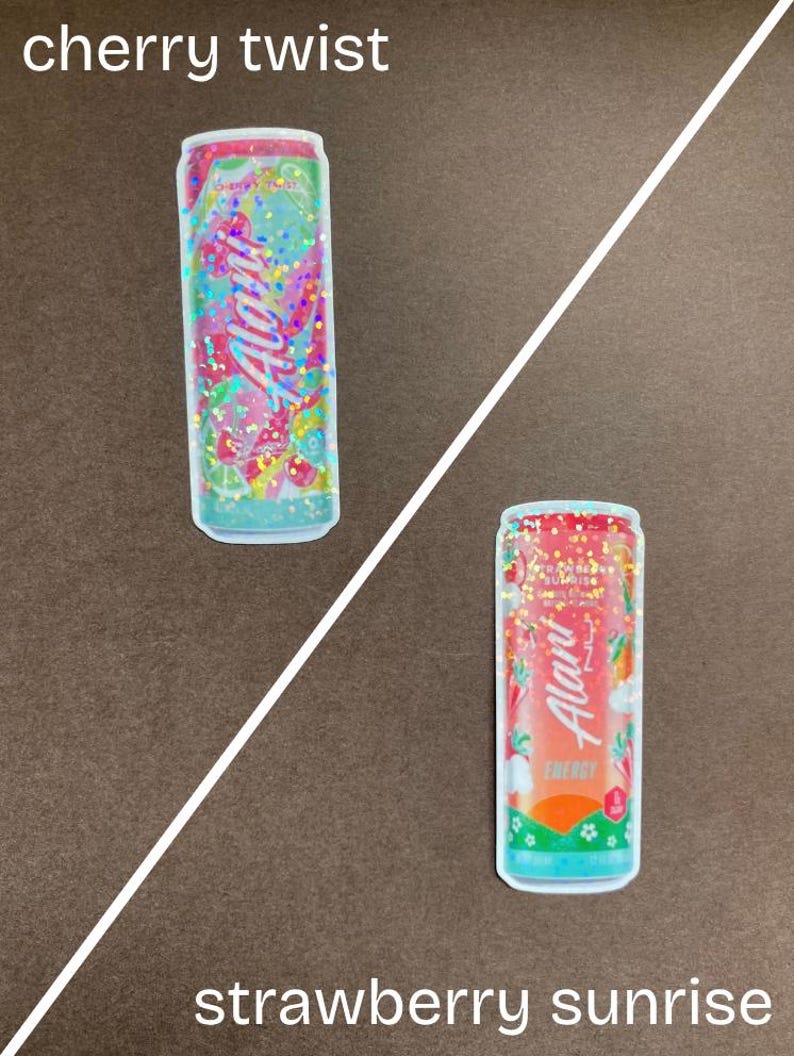 May include: Two colorful can stickers with glitter. The first sticker is pink and green with the text "Cherry Twist" and the second sticker is orange and red with the text "Strawberry Sunrise".