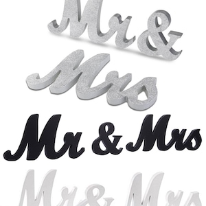 May include: Four decorative Mr & Mrs signs in silver glitter, black, and white. The silver glitter signs have a sparkling finish. The black and white signs have a matte finish. All signs are in a cursive font, perfect for wedding decor.