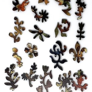 May include: A set of 17 wooden jigsaw puzzle pieces featuring intricate floral and bird designs. The pieces are painted in a variety of colors, including brown, blue, green, and red. The pieces are all different shapes and sizes, and they are all cut out in a way that makes them fit together perfectly.