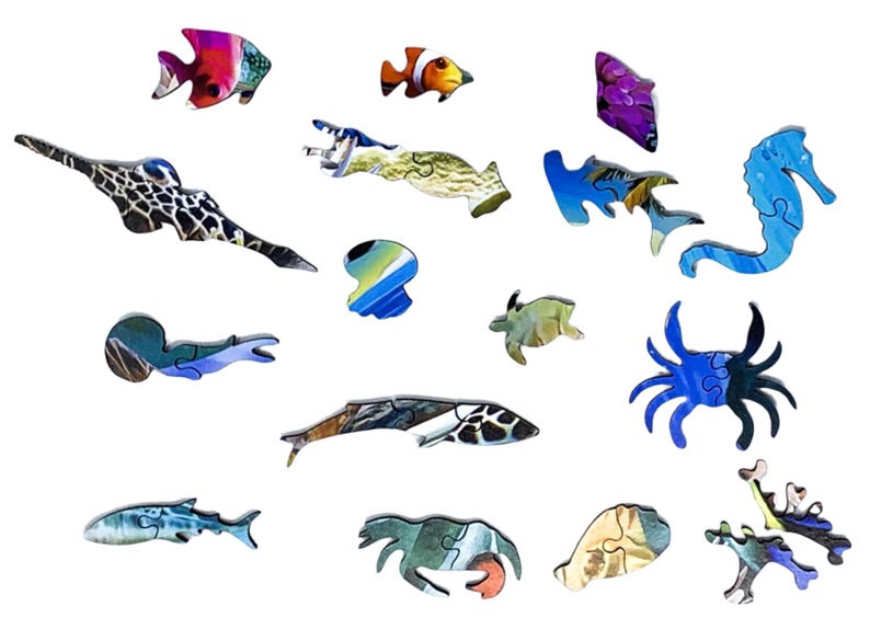 May include: Wooden jigsaw puzzle pieces in the shape of various sea creatures, including fish, a seahorse, and a crab. The pieces are painted with vibrant colors and detailed patterns, creating a visually appealing puzzle.