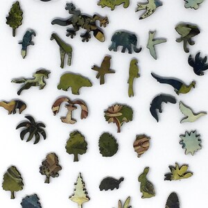 May include: A wooden jigsaw puzzle with a variety of animal and plant shapes. The pieces are painted in a variety of colors, including green, blue, and brown. The puzzle is made up of 30 pieces.
