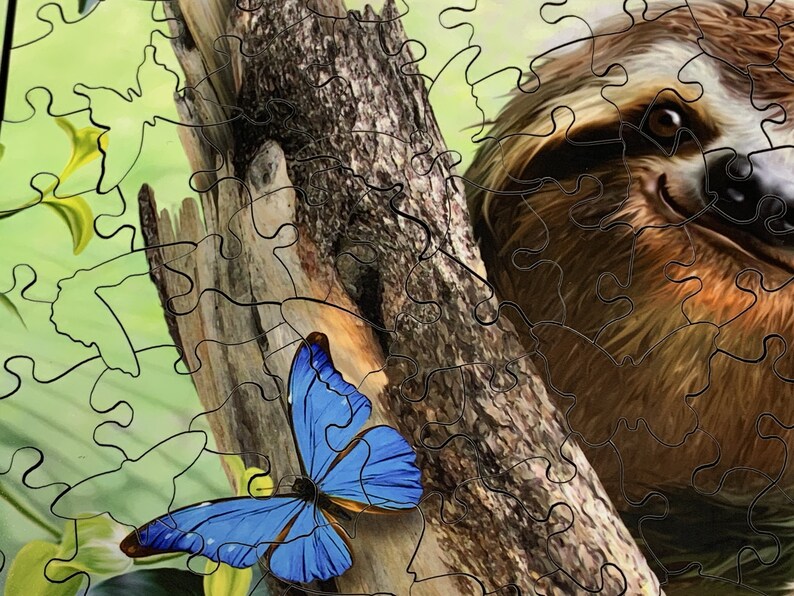 May include: A jigsaw puzzle featuring a sloth and a blue butterfly. The sloth is brown and tan, with a focused gaze. The butterfly has bright blue wings with black edges. The puzzle pieces are visible, creating a textured effect.