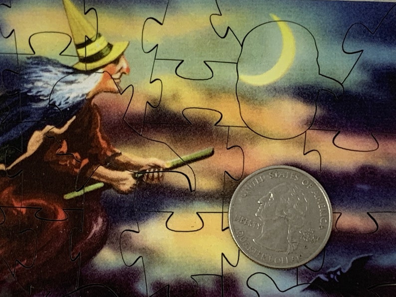 Może przedstawiać: Element układanki z ilustracją w stylu vintage przedstawiającą wiedźmę na miotle na tle nocnego nieba z p&oacute;łksiężycem. Z przodu znajduje się moneta o nominale 25 cent&oacute;w.
