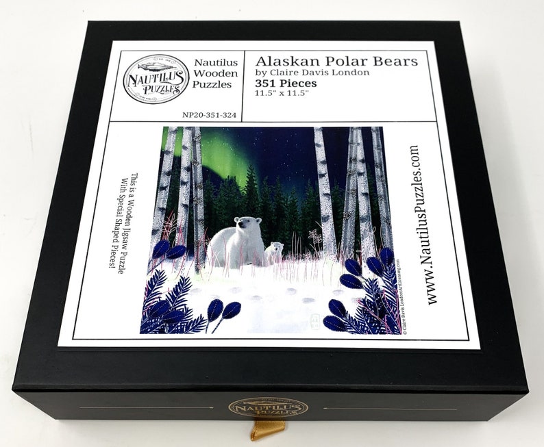 May include: A wooden jigsaw puzzle box featuring a snowy scene with two polar bears in a birch forest under a starry sky with a green aurora borealis. The box is black with a white label that reads "Alaskan Polar Bears by Claire Davis London 351 Pieces 11.5" x 11.5" NP20-351-324 This is a Wooden Jigsaw Puzzle with Special Shaped Pieces! www.NautilusPuzzles.com".
