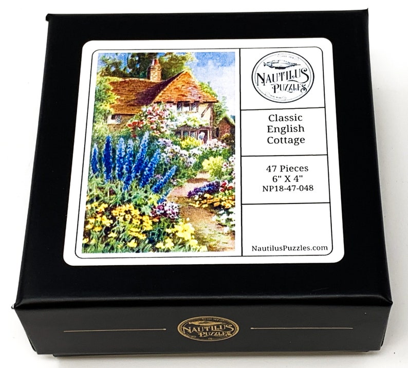 Puede incluir: Caja negra de rompecabezas con una imagen de una casa de campo inglesa cl&aacute;sica rodeada de flores. La caja est&aacute; etiquetada como "Classic English Cottage", con 47 piezas y mide 15 cm x 10 cm. La marca "Nautilus Puzzles" tambi&eacute;n es visible.