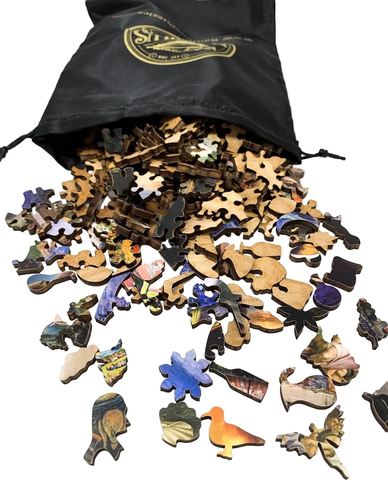 May include: A black drawstring bag with a gold logo spills out wooden jigsaw puzzle pieces. The pieces are various shapes and sizes, with colorful images of art and landscapes. The puzzle pieces are scattered on a white surface.